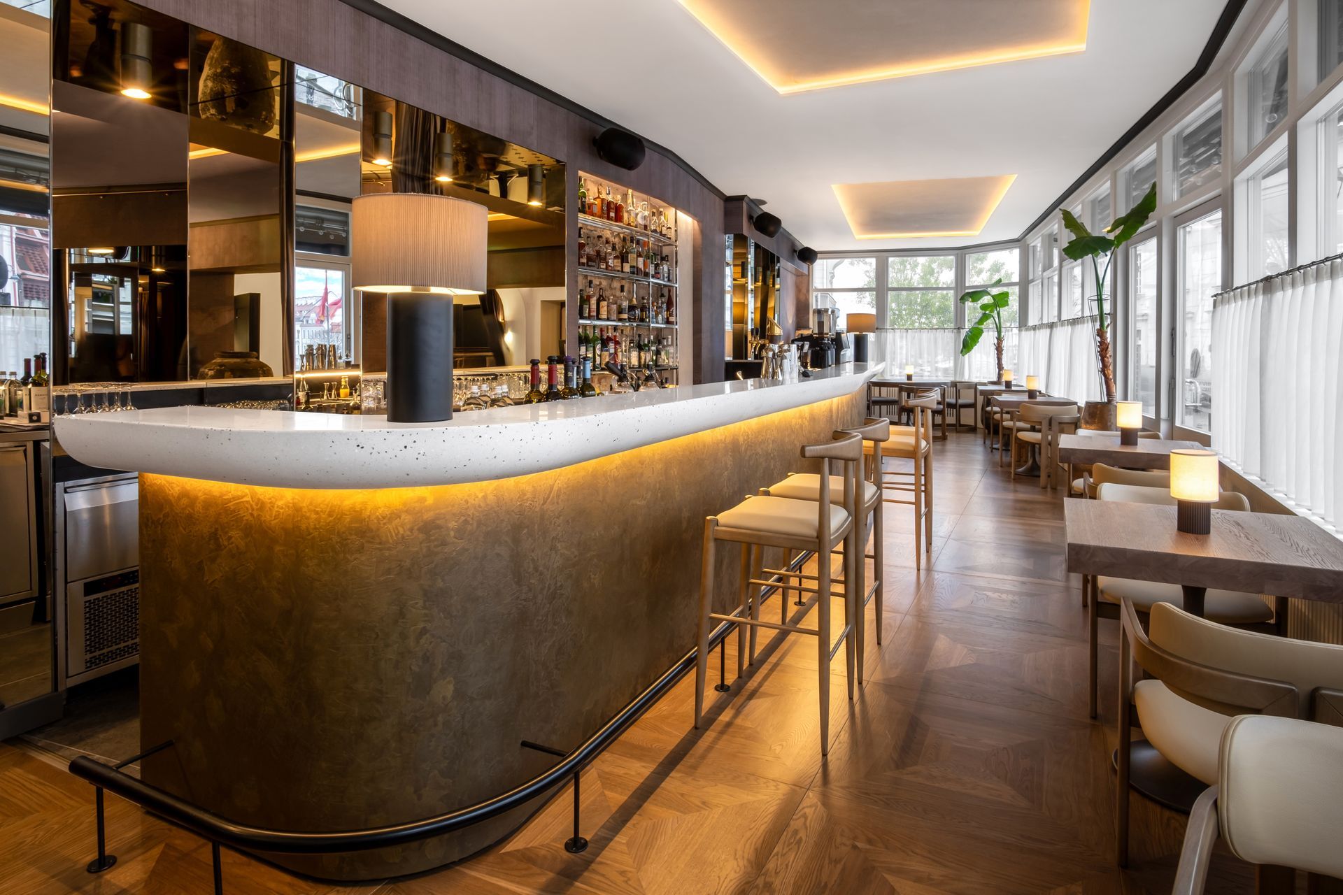 Restoranas su ilgu baru, stalais ir kėdėmis.