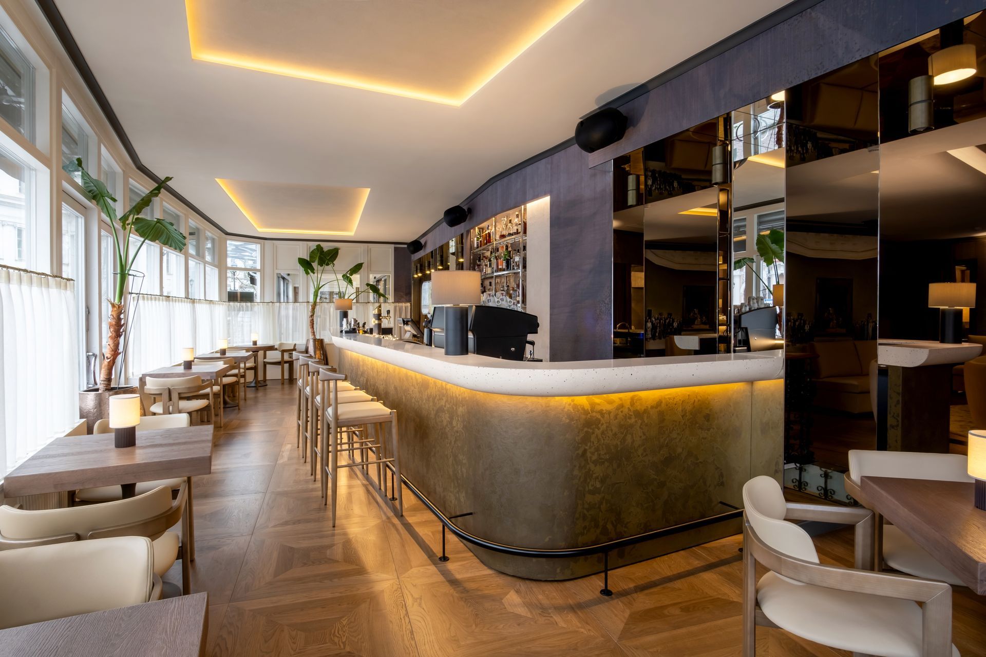 Restoranas su ilgu baru, stalais ir kėdėmis.