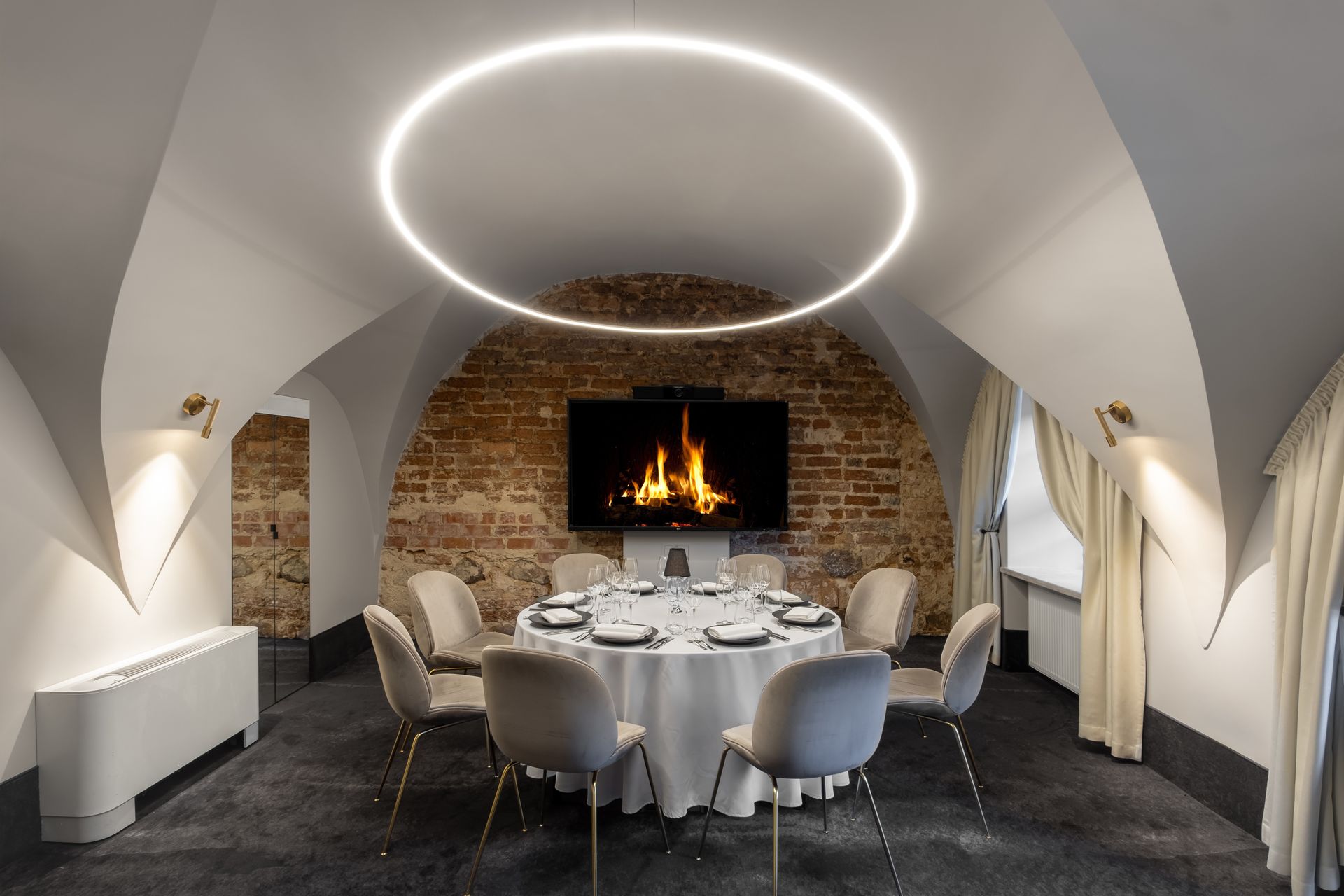 Valgomasis su apvaliu stalu, kėdėmis ir židiniu.