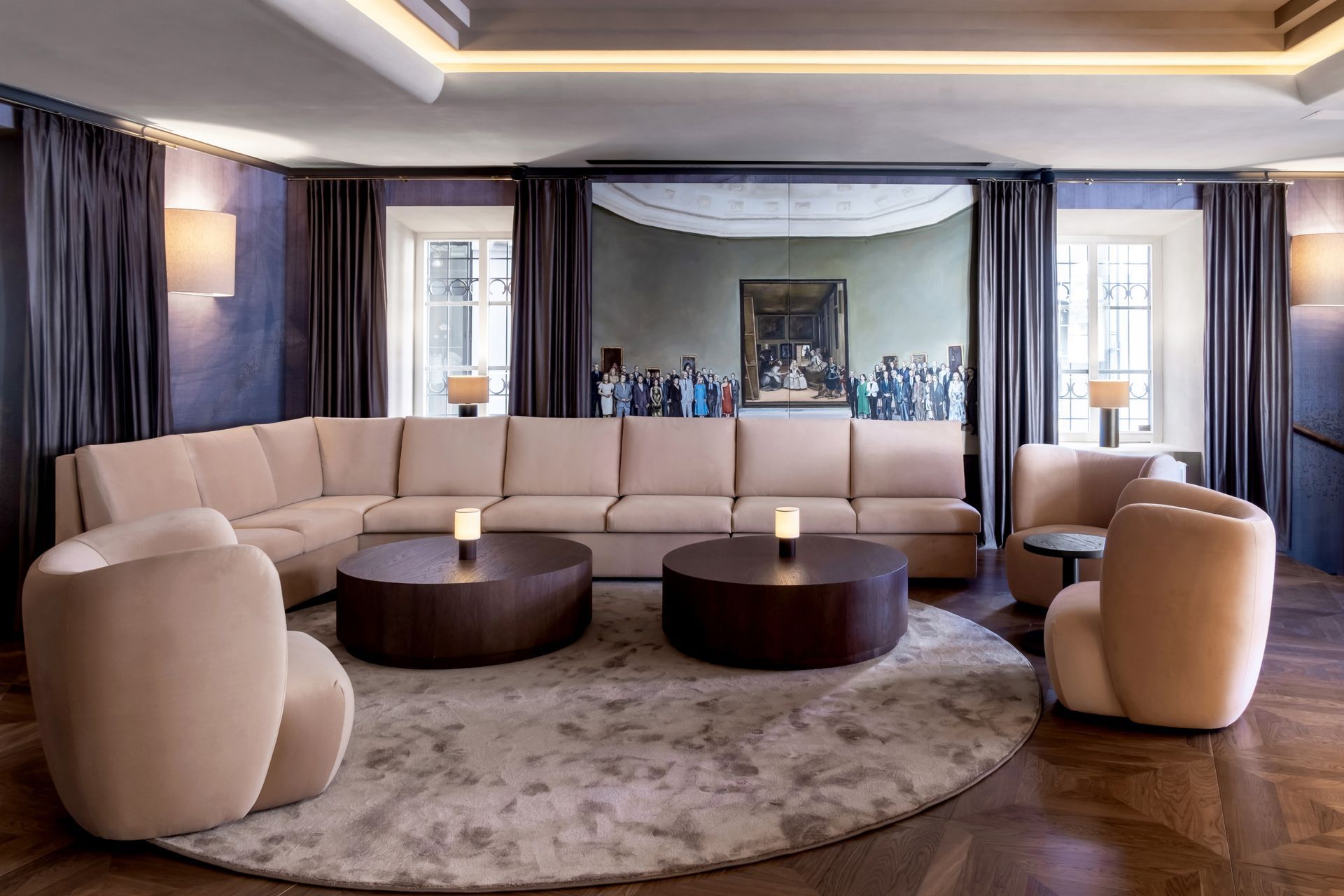 Svetainė su sofa, kėdėmis, stalais ir apvaliu kilimu.