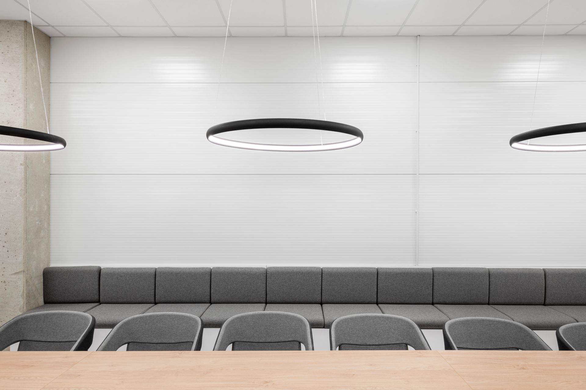 Laukimo kambarys su ilga sofa, kėdėmis ir stalu.