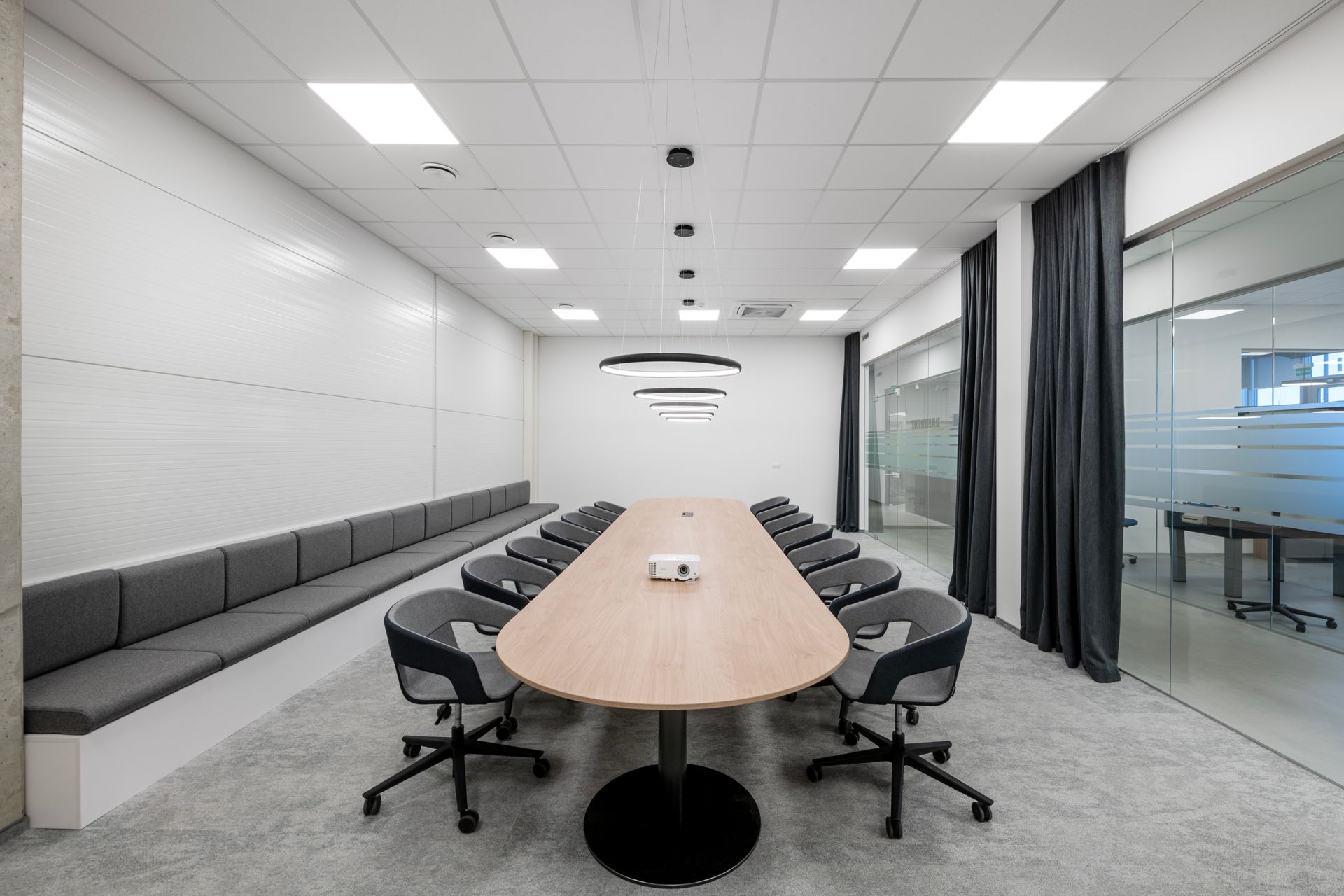 Konferencijų salė su ilgu mediniu stalu ir kėdėmis.