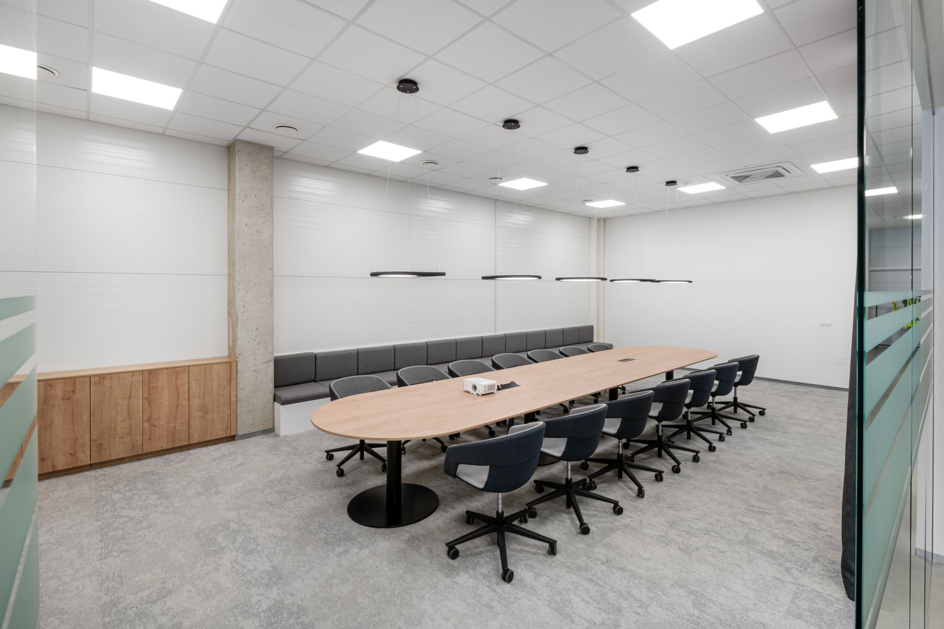 Konferencijų salė su ilgu stalu ir kėdėmis.