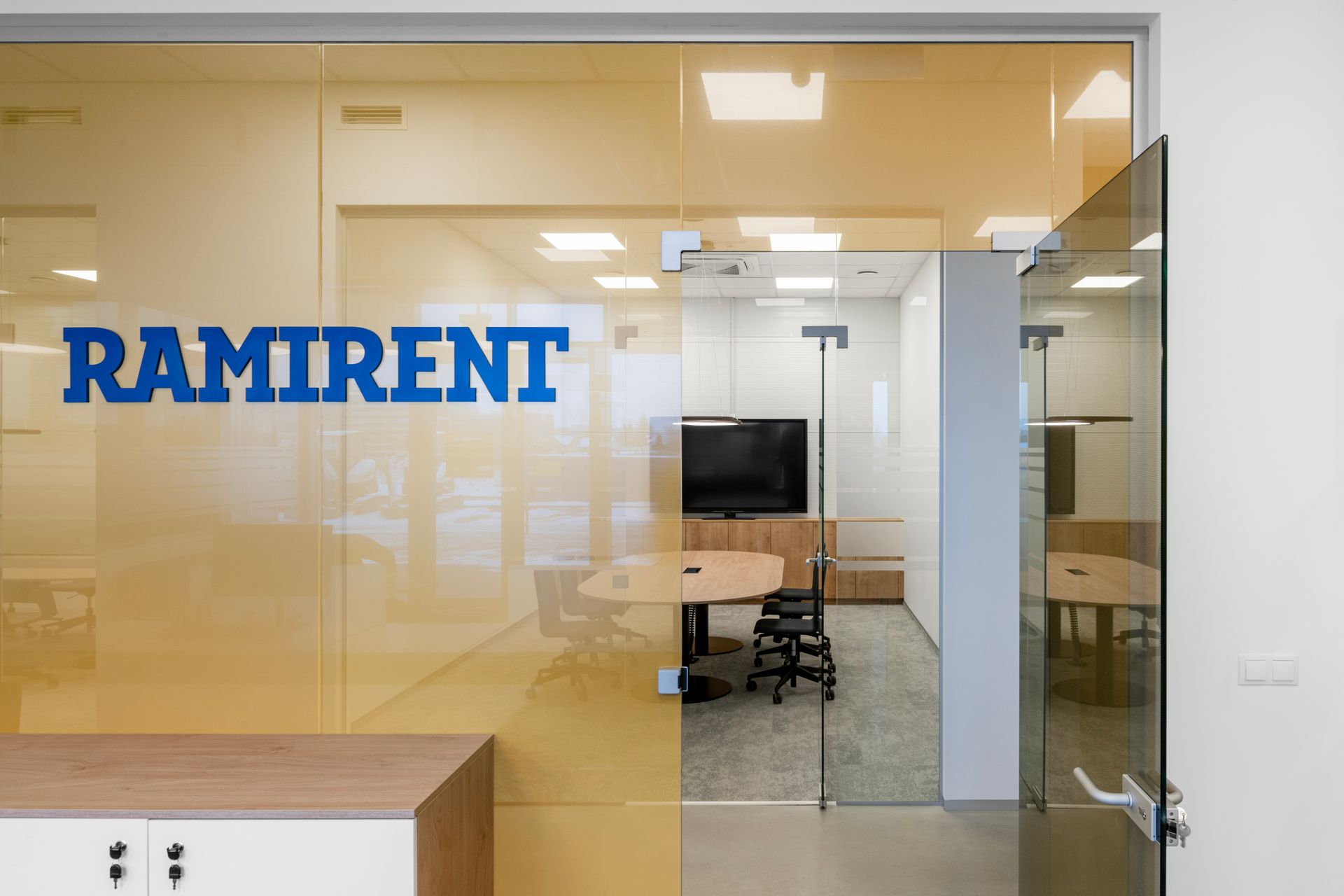 Kambarys su stiklinėmis durimis ir užrašu „ramirent“.