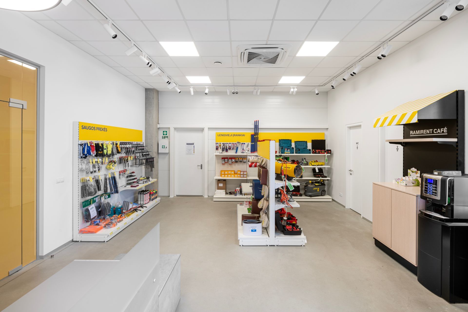 Didelis kambarys su daugybe lentynų ir stalviršiu.