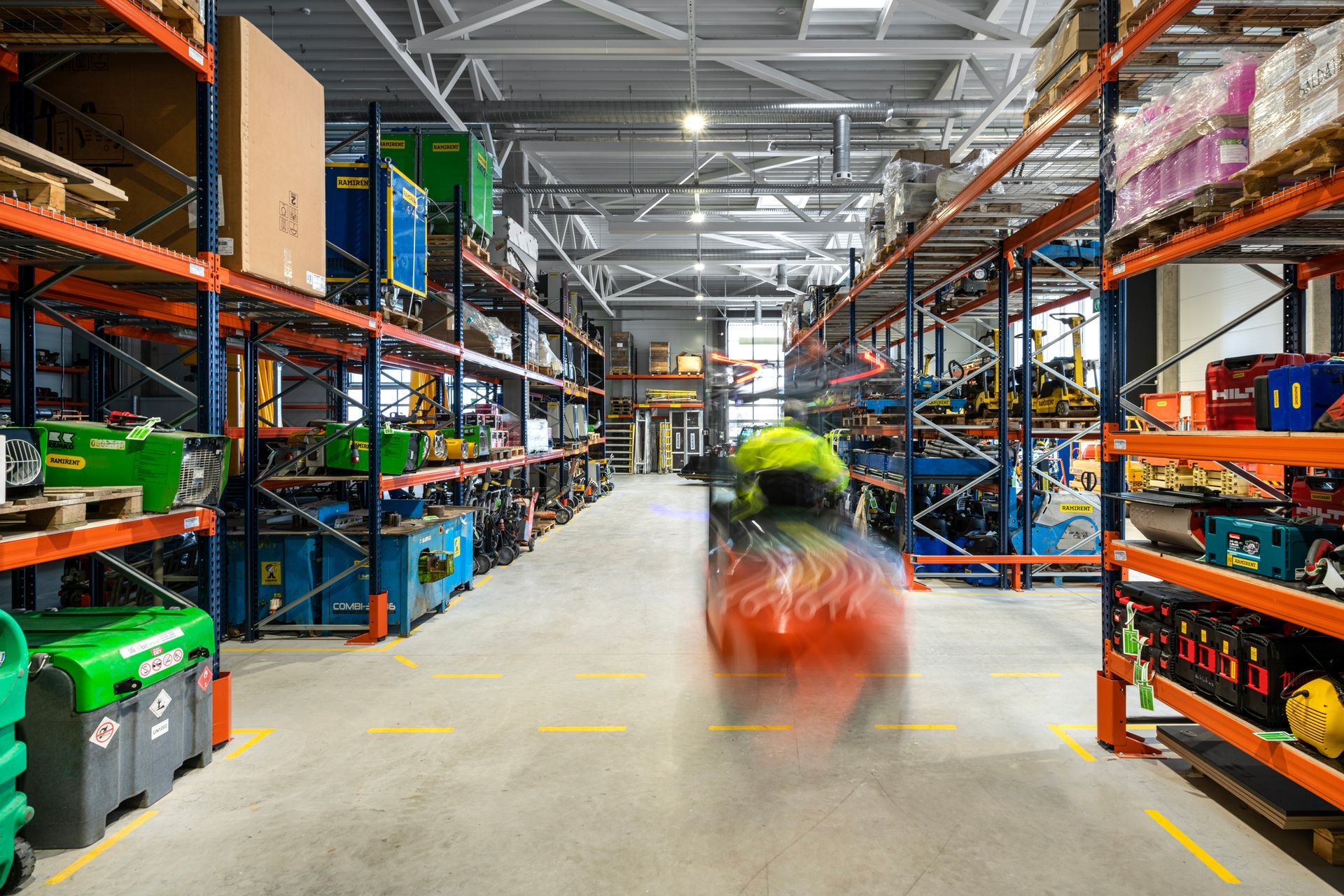 Vyras vairuoja šakinį krautuvą sandėlyje.