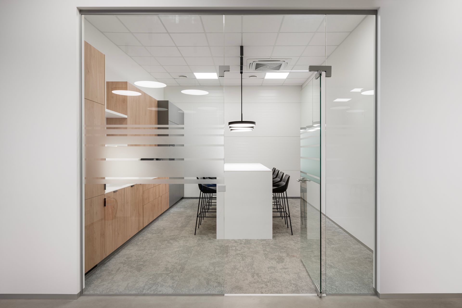 Konferencijų salė su stiklinėmis durimis, stalu ir kėdėmis.