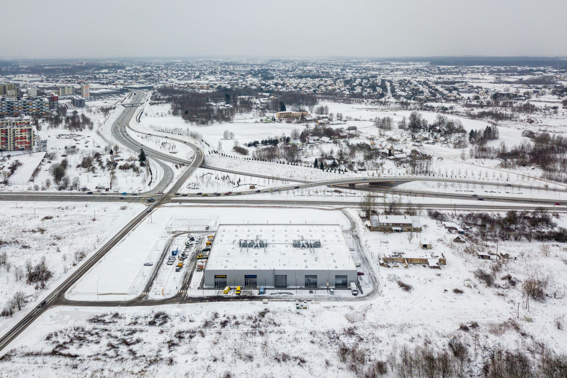 Pastato, esančio apsnigto lauko viduryje, vaizdas iš oro.