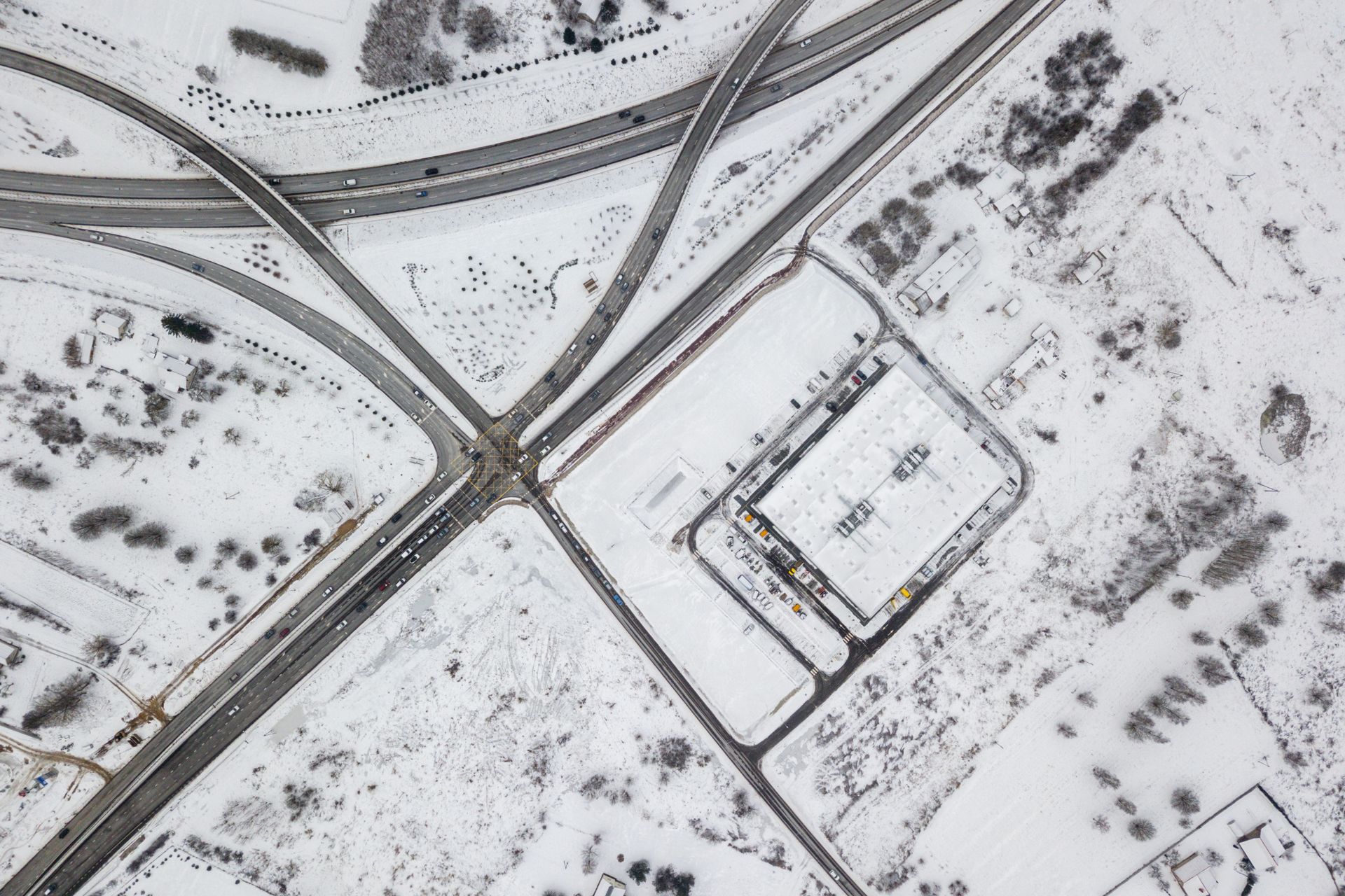 Apsnigtos sankryžos vaizdas iš oro, kai ant žemės yra daug sniego.