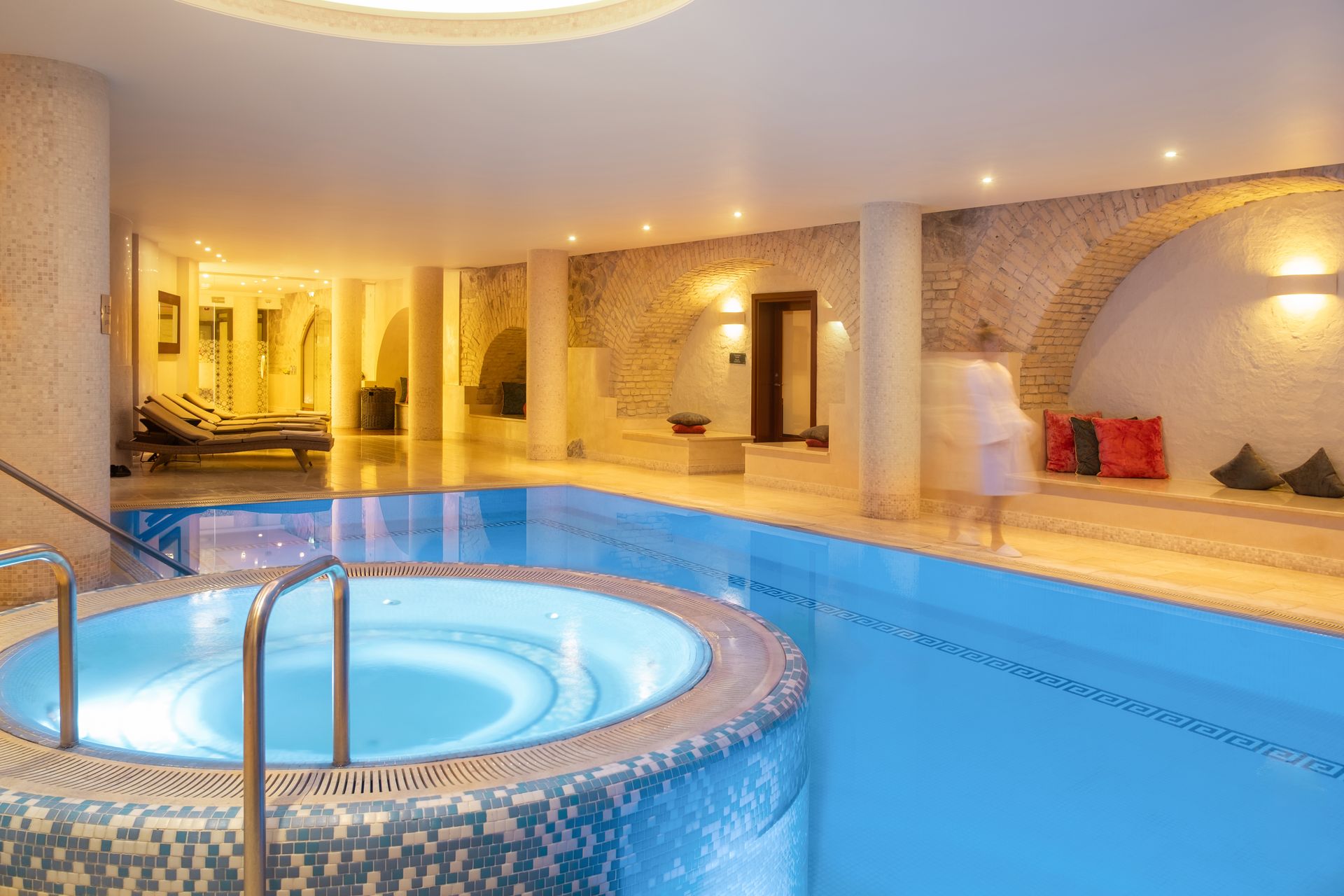 Didelis uždaras baseinas su sūkurine vonia viduryje.