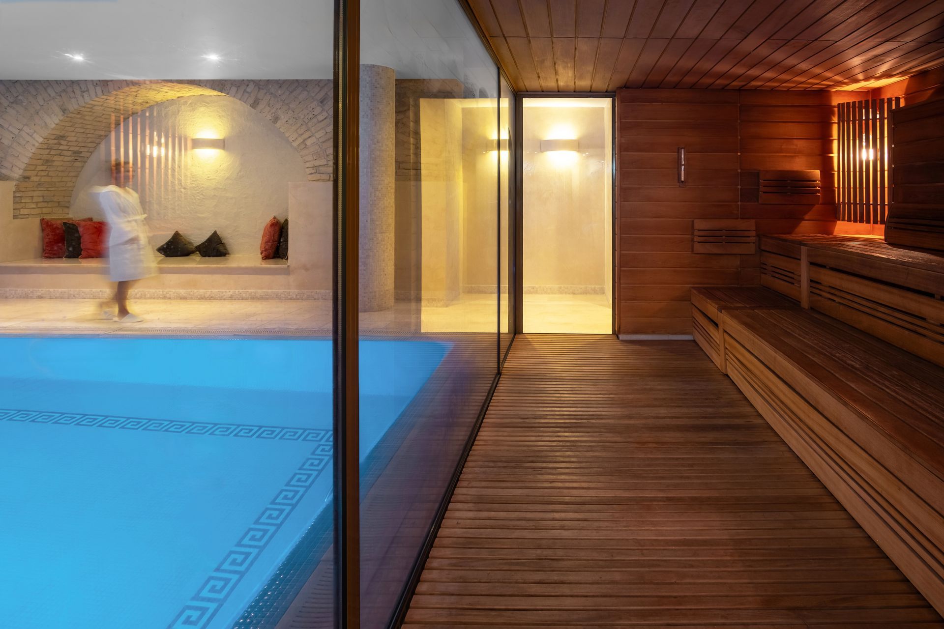Moteris su chalatu stovi prie baseino saunoje.