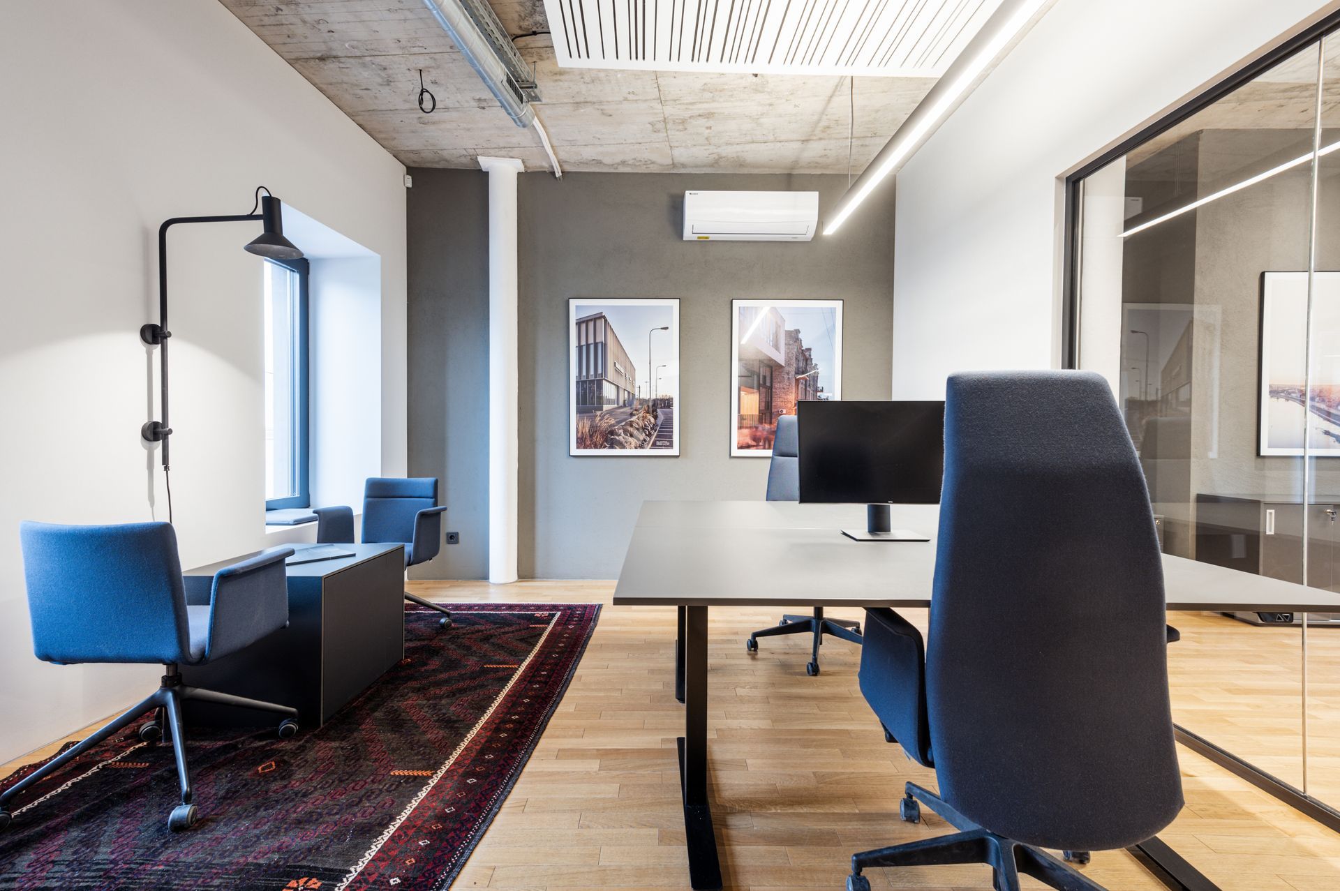 Konferencijų salė su stalu, kėdėmis ir kompiuteriu.