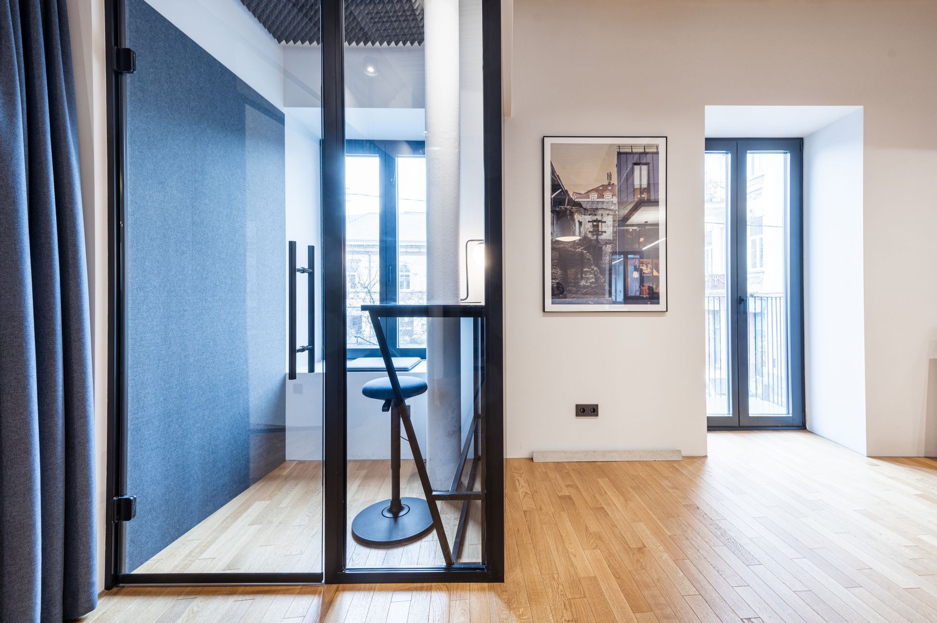 Kambarys su stiklinėmis durimis ir paveikslu ant sienos.