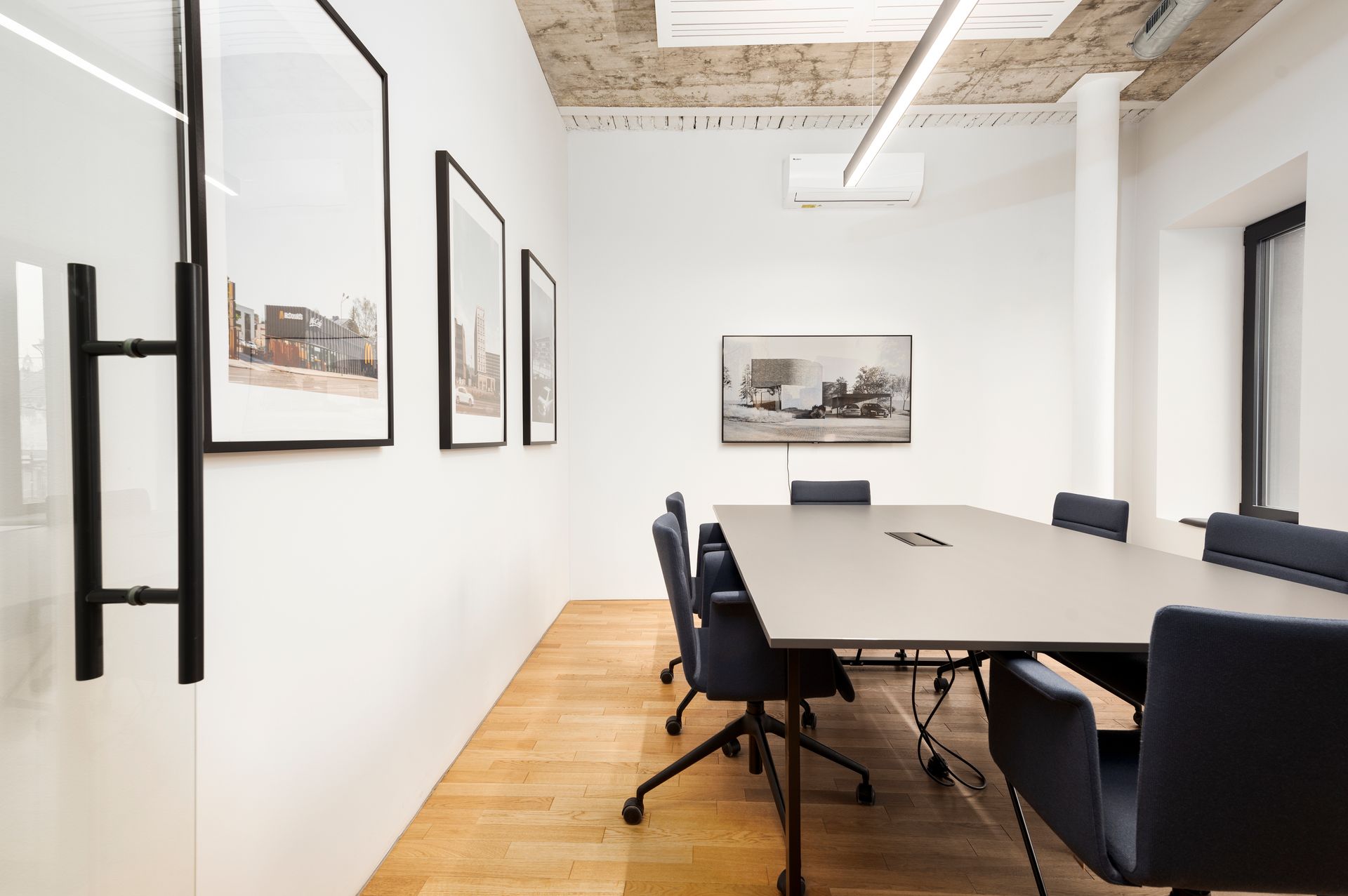 Konferencijų salė su ilgu stalu ir kėdėmis.