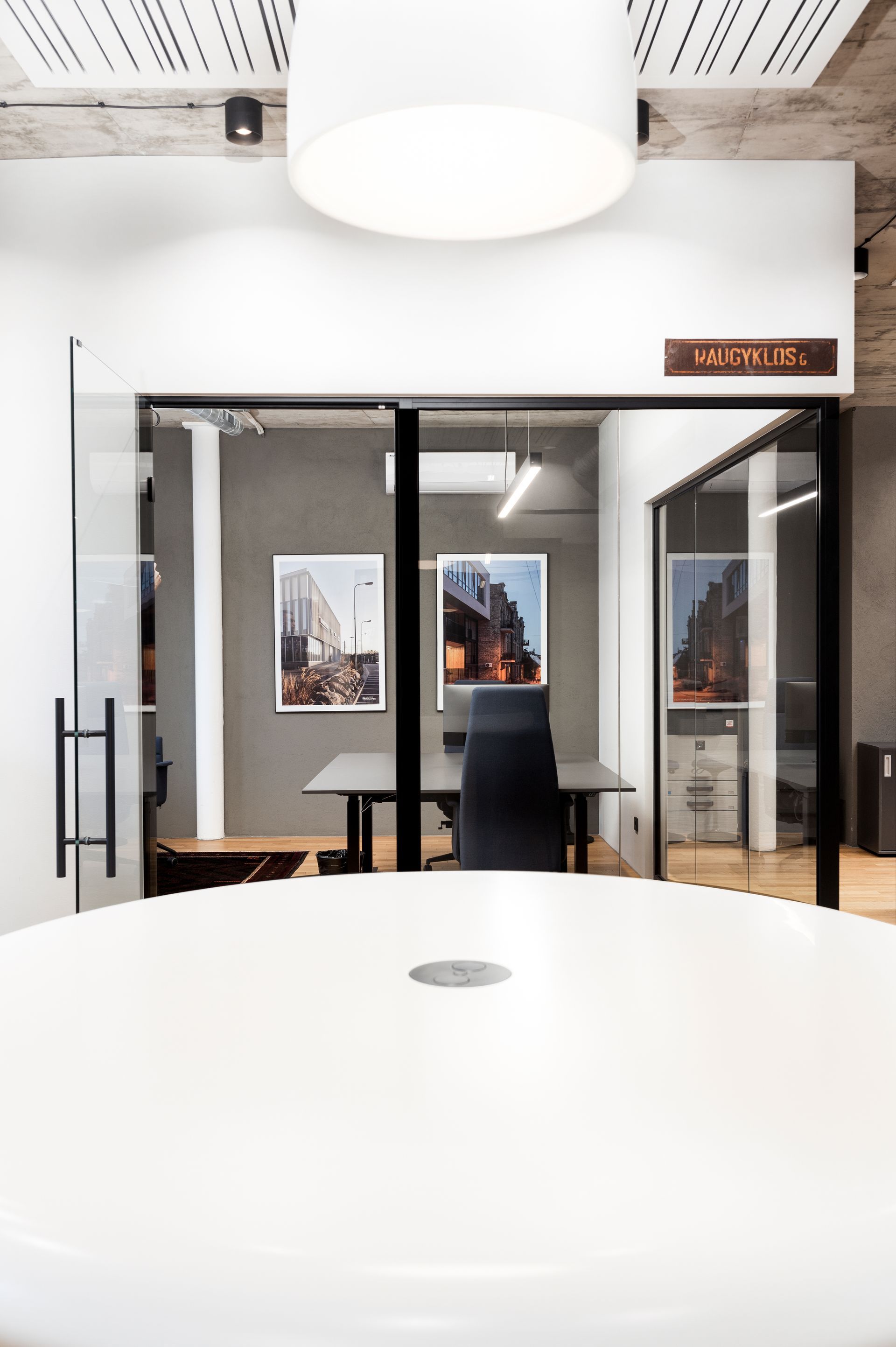 Konferencijų salė su apvaliu stalu ir kėdėmis.