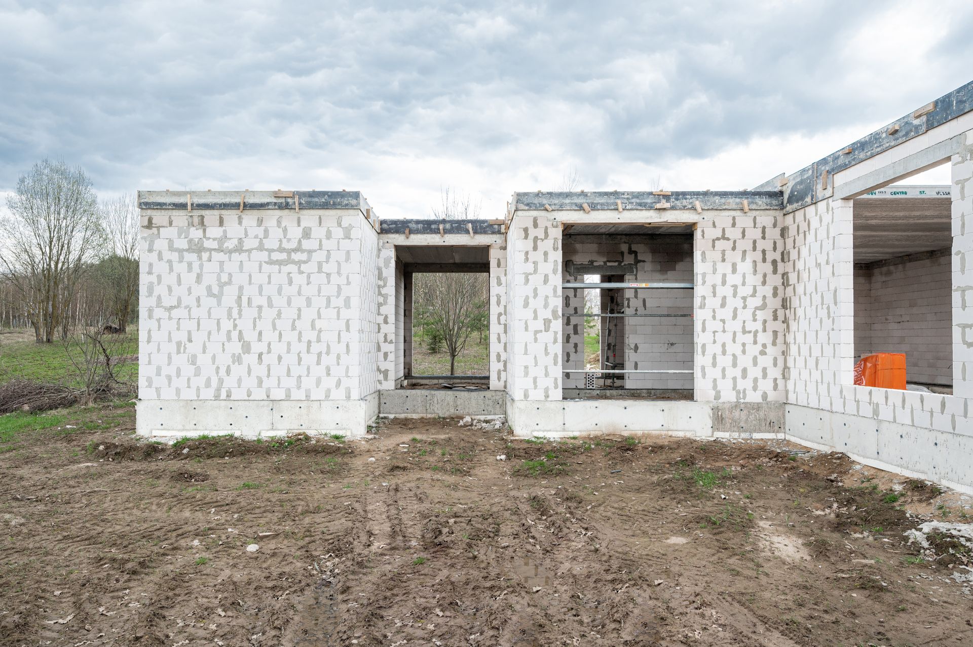 Žemės lauke statomas baltų plytų namas.