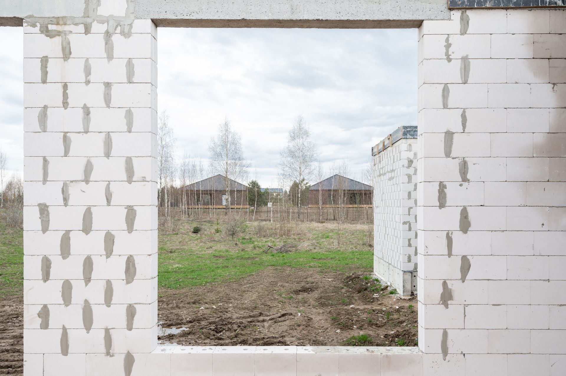 Lauko vaizdas pro statomo pastato langą.