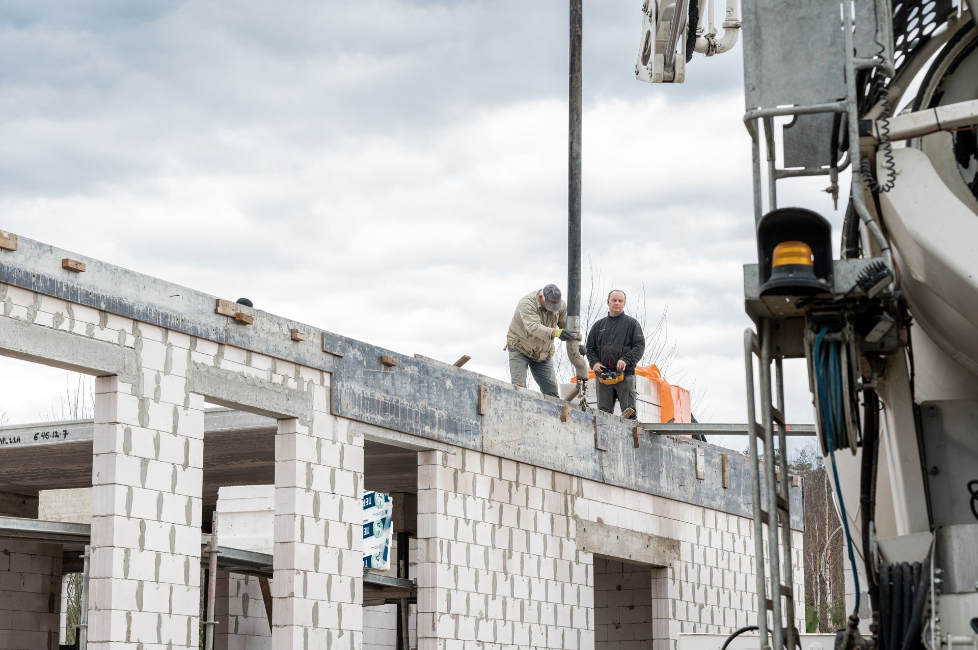 Statybininkų grupė dirba prie statomo pastato.
