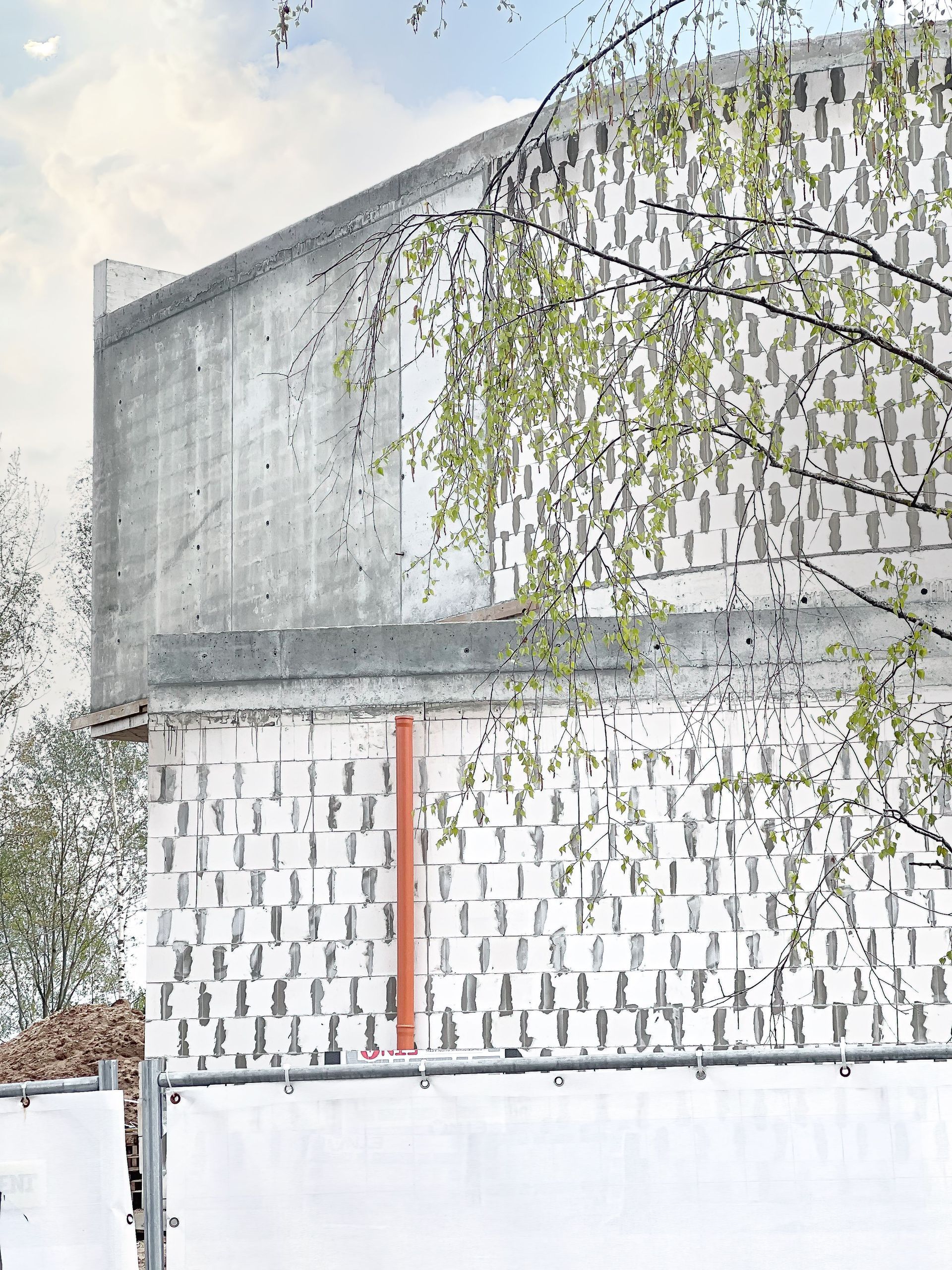 Didelis baltas pastatas su tvora priešais ir medžiais fone.