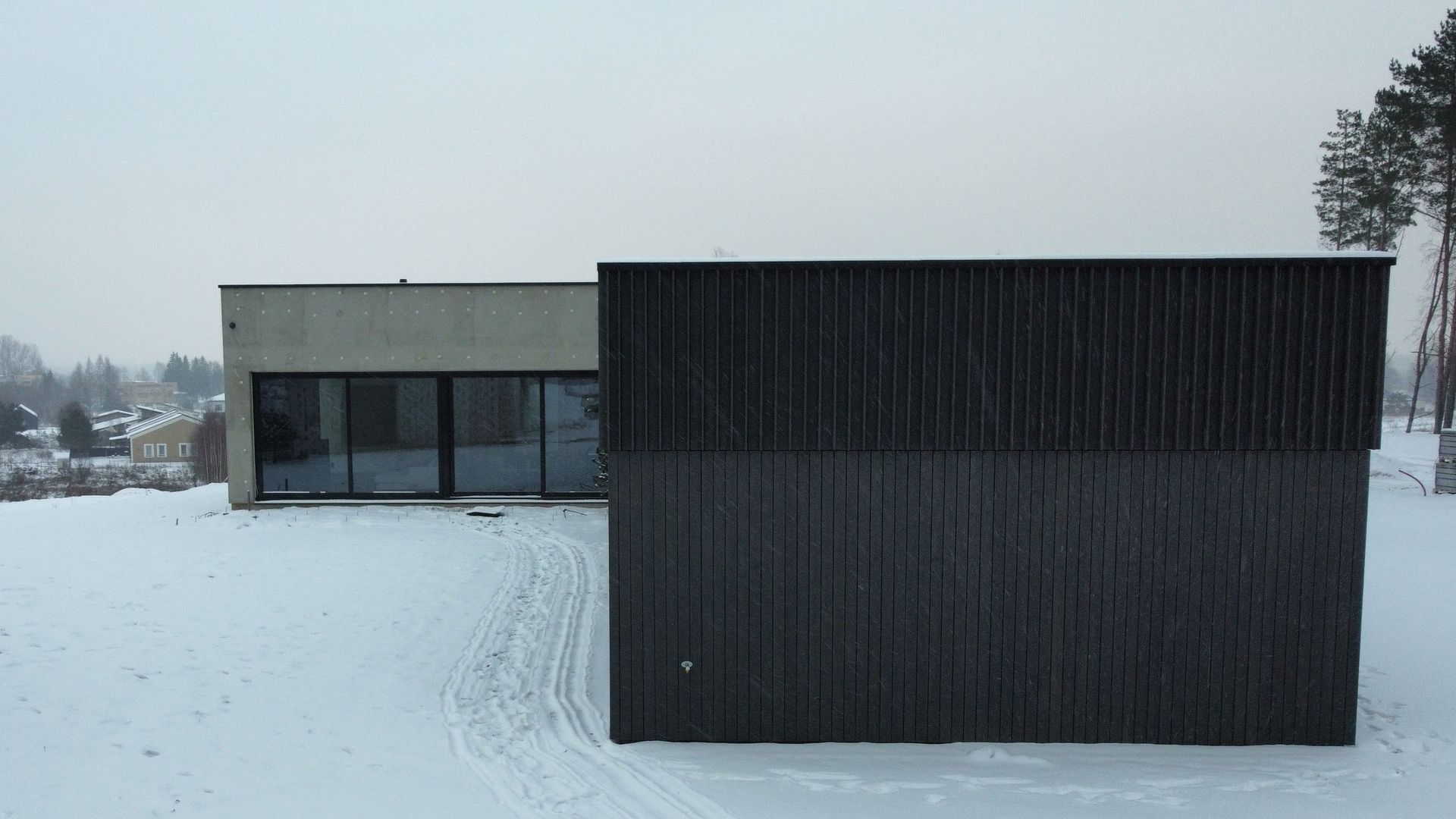 Juodas namas stovi sniegu padengto lauko viduryje.