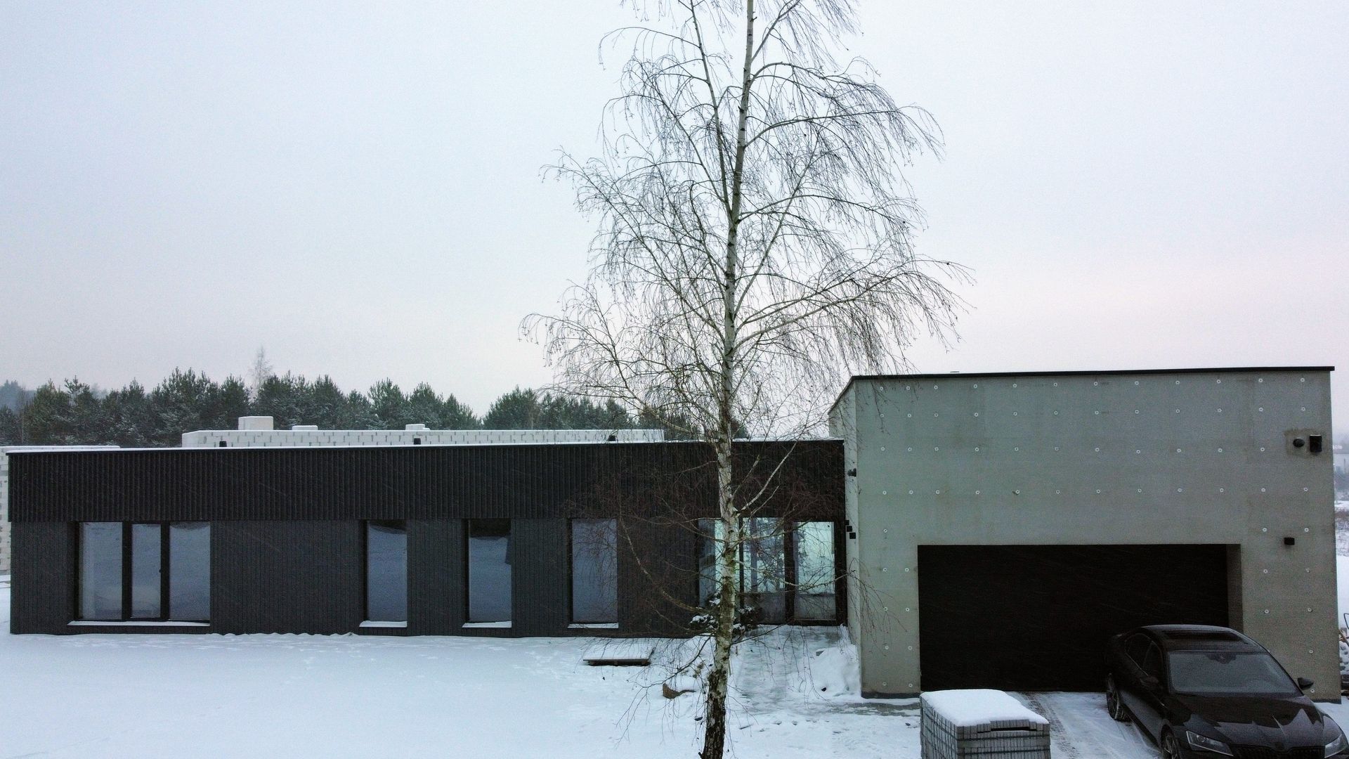 Automobilis stovi priešais namą sniege.