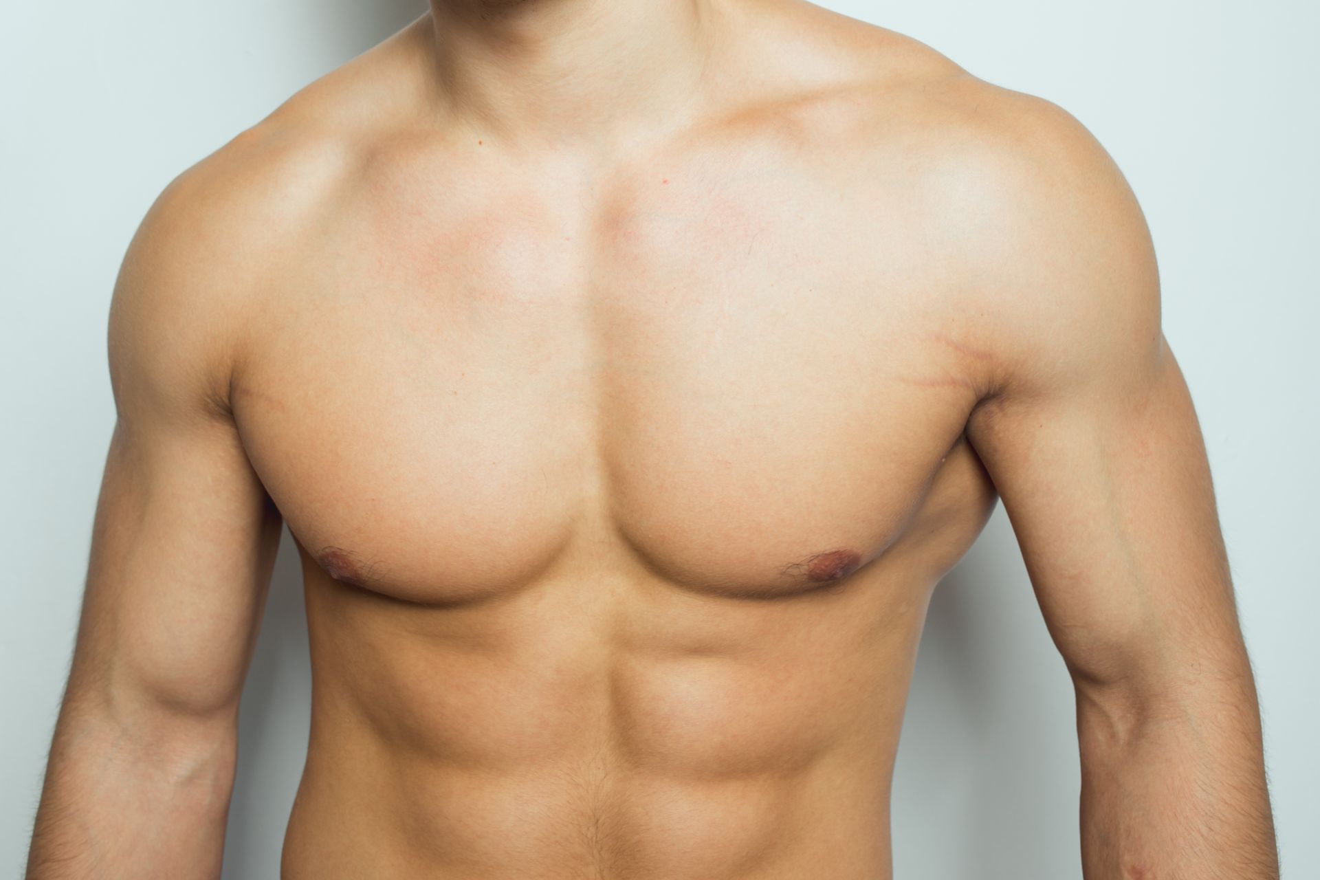 Bare-chested torso with defined chest, abs, and arms against a plain light background