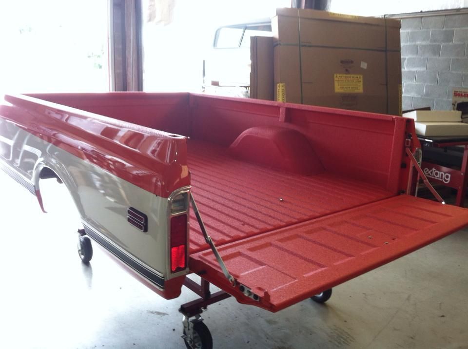 A red truck bed is sitting on a cart in a garage