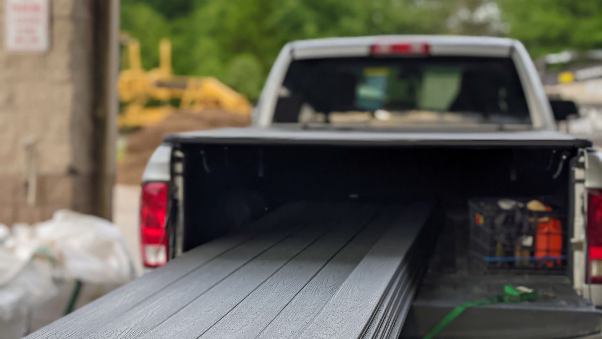 A truck is carrying a stack of lumber in its bed.