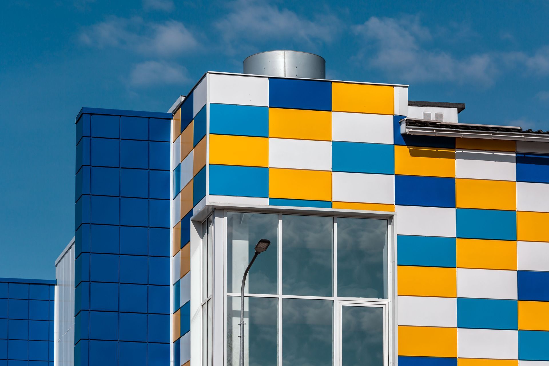 Modern building facade with blue, white, and orange checkerboard panels and large windows
