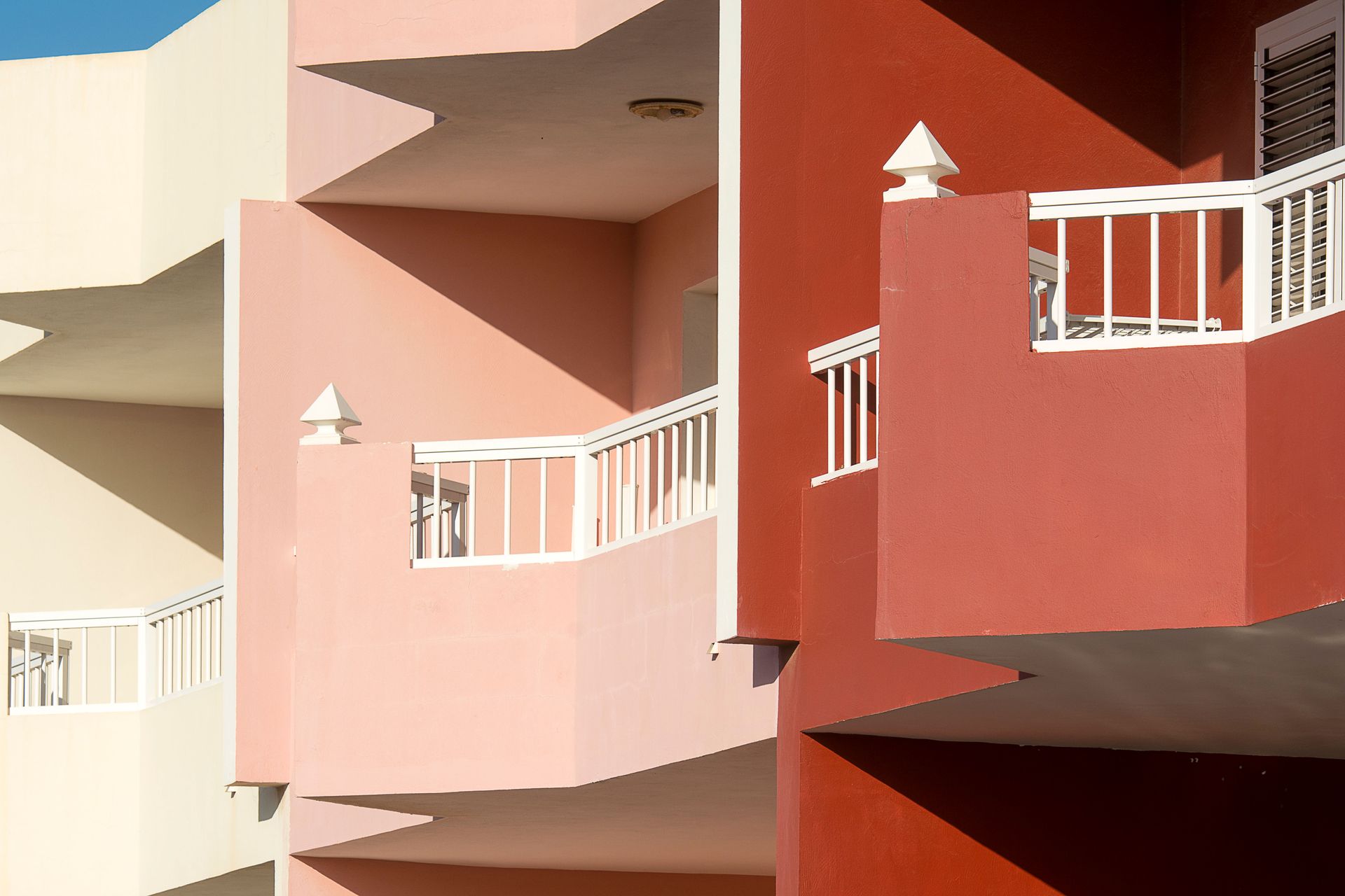 Pastel apartment balconies with white railings on a modern building facade
