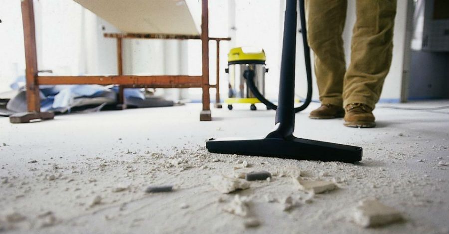 A man is cleaning the floor with a vacuum cleaner.