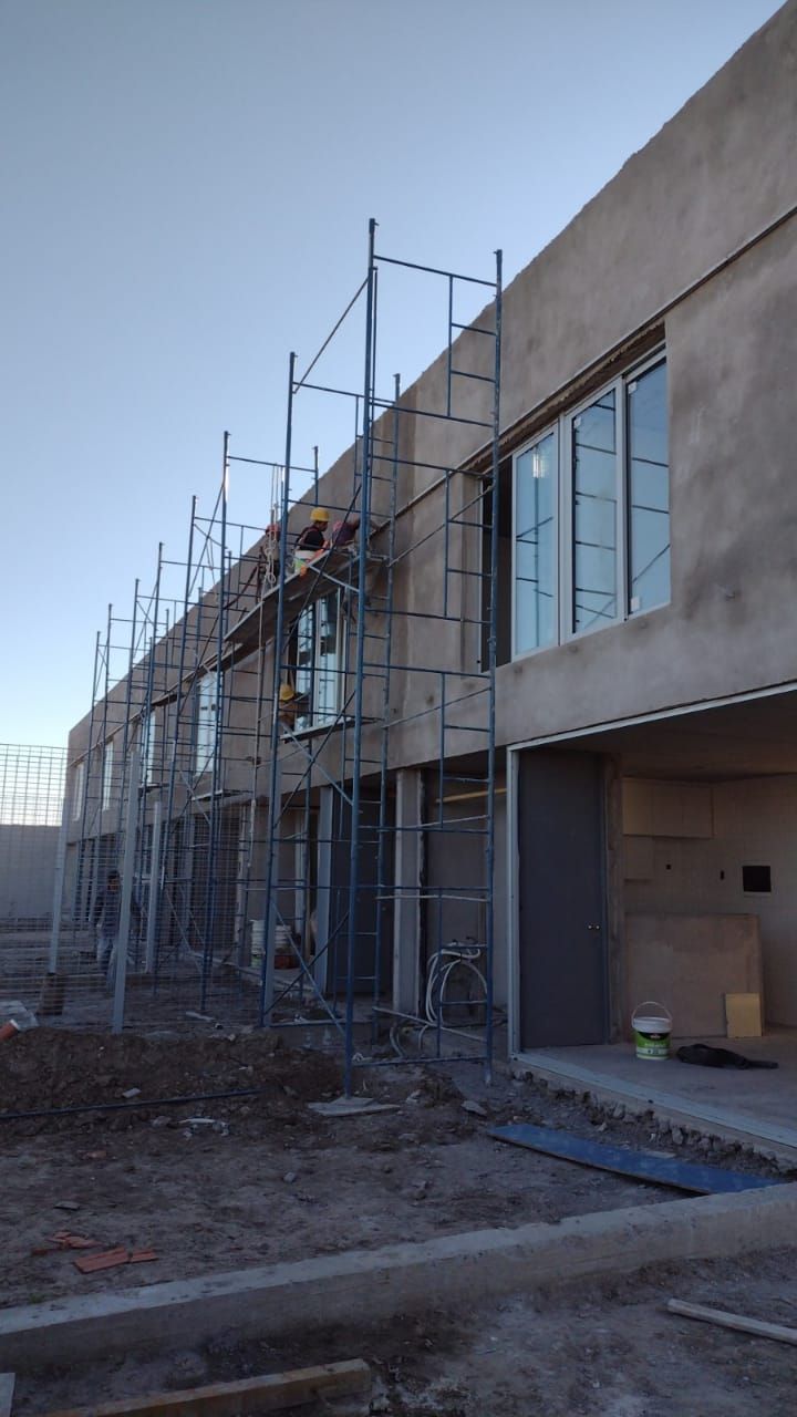 Hilera de edificios sin terminar con andamios contra el exterior de estuco; sitio de construcción.