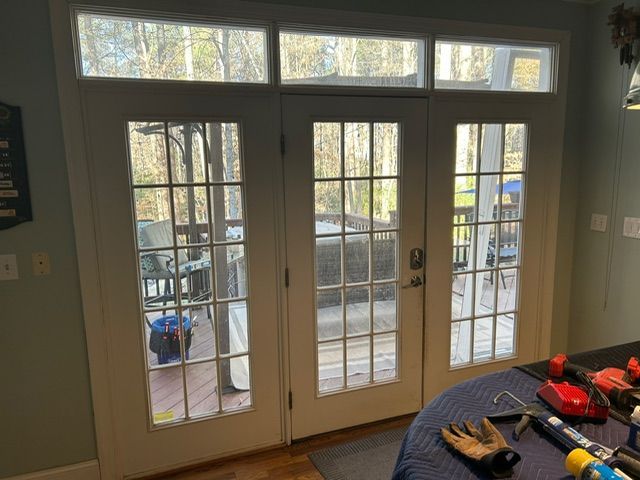 Three white French doors with glass panes and a transom window above, opening to a deck.