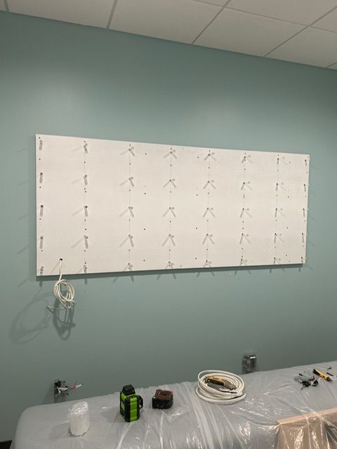 White panel with lights installed on a teal wall, electrical wires visible, construction in progress.