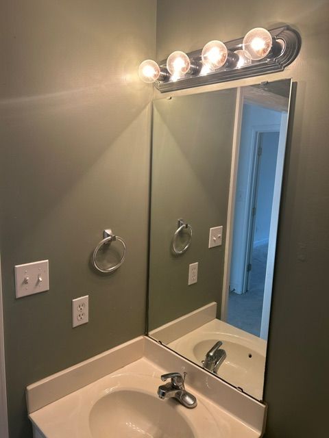 Bathroom with sink, mirror, and light fixture; neutral walls.