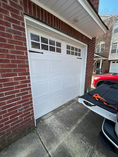 White garage door with windows, on a brick building, with a truck tailgate open.