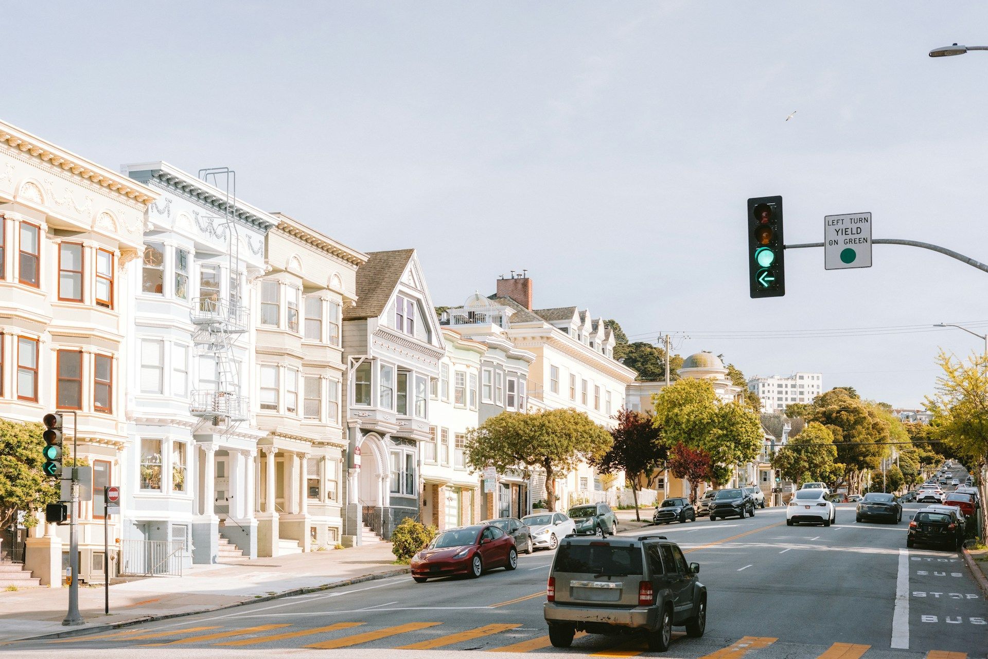 A busy city street with cars driving down it and a green traffic light.