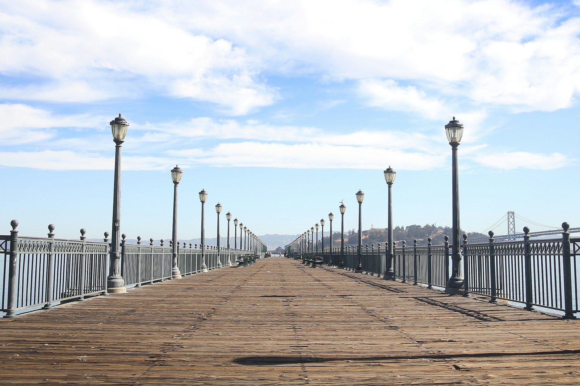 A long wooden pier with a fence and lots of street lights
