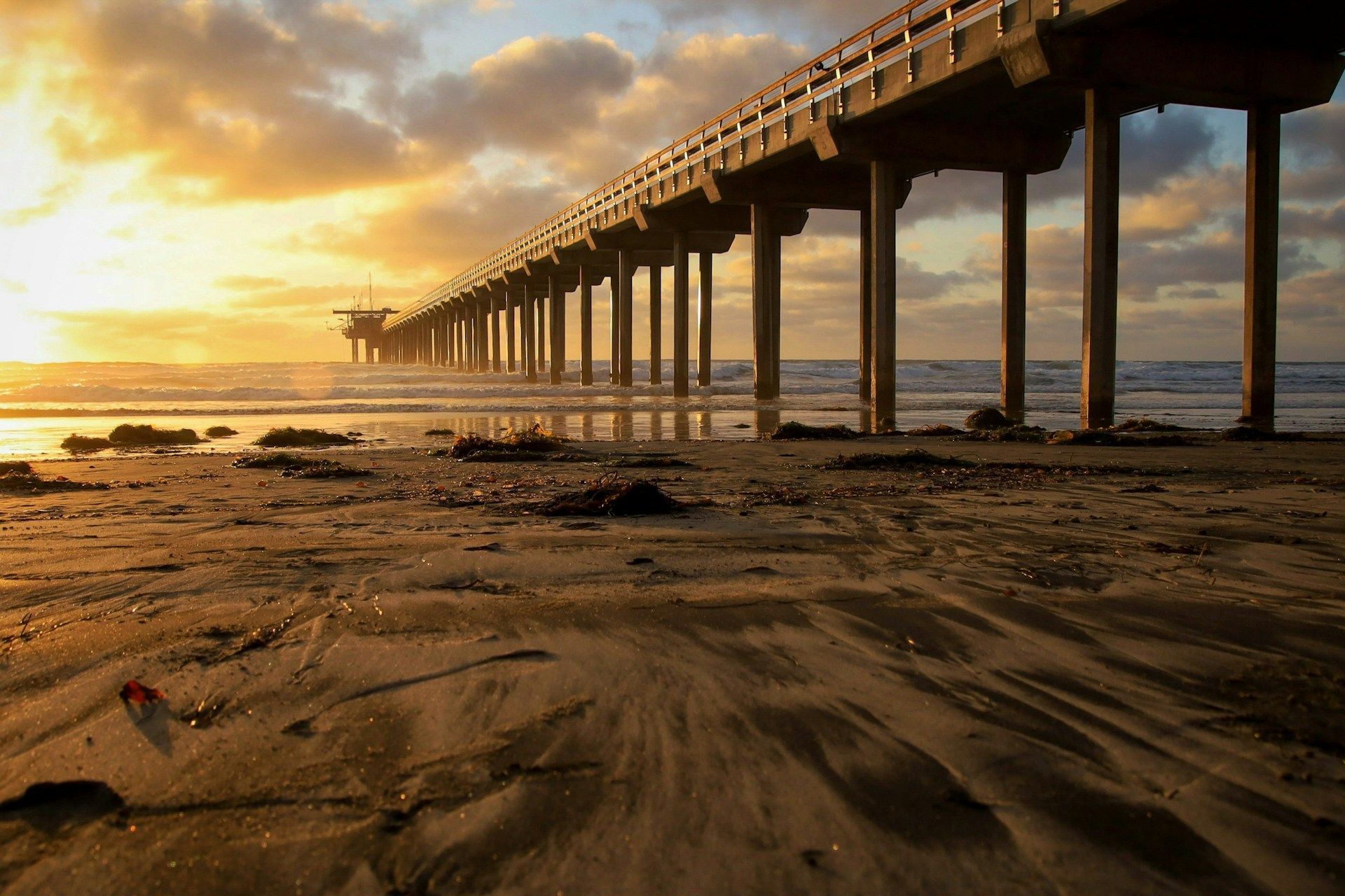 A pier on a beach with a sunset in the background