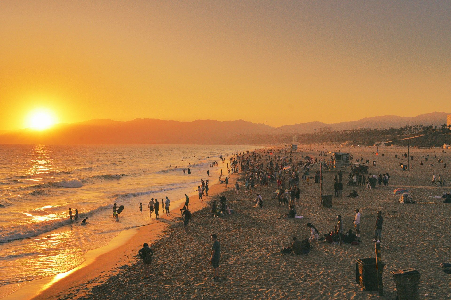 A group of people are walking on a beach at sunset.