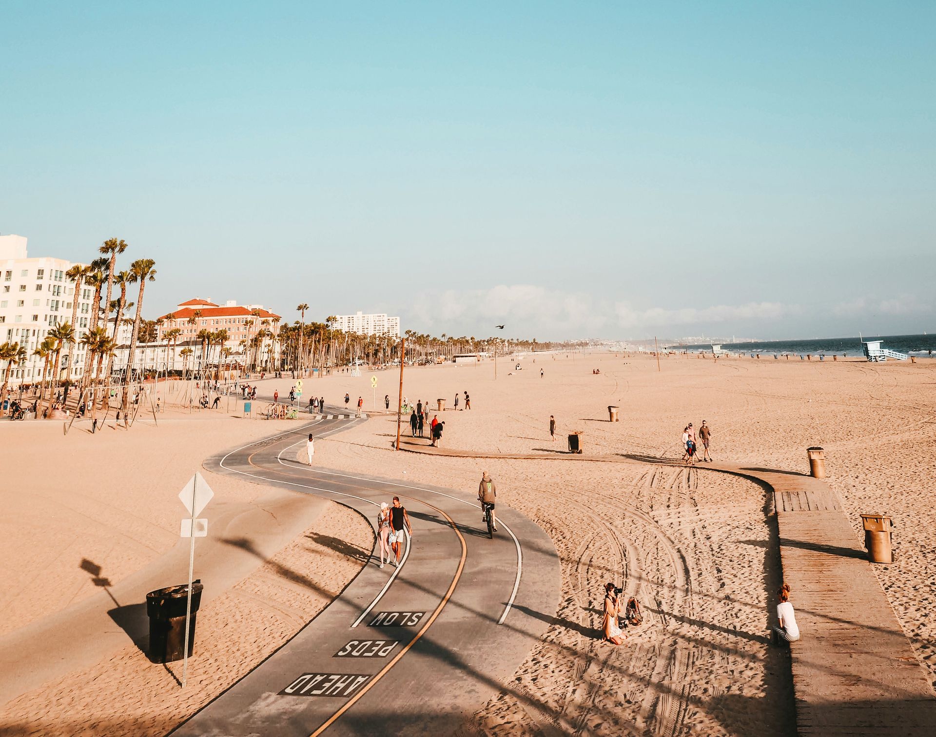 A group of people are walking along a path on the beach.