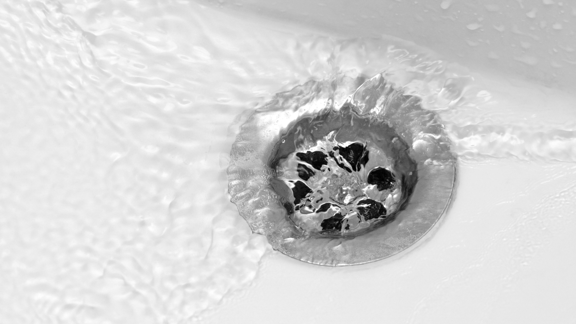 A close up of a sink drain with water running down it.
