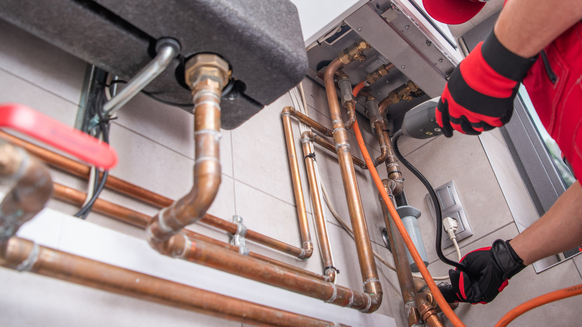 A plumber is working on a boiler in a room.