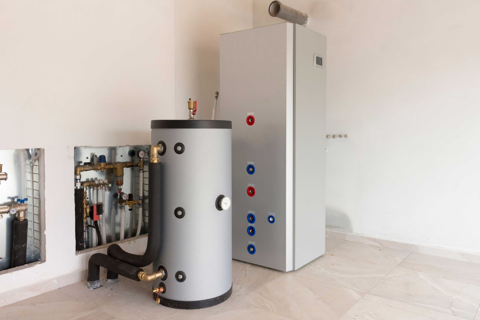 A water heater and a tall, metal unit in a white-walled room, likely a utility space.