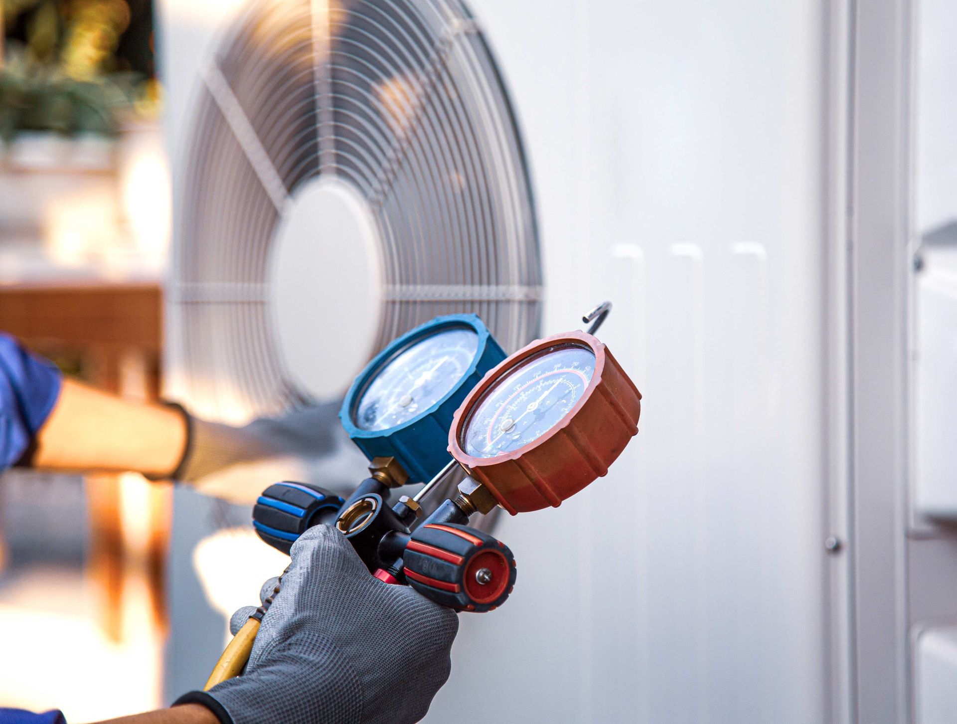 HVAC technician using gauges on an outdoor air conditioning unit.
