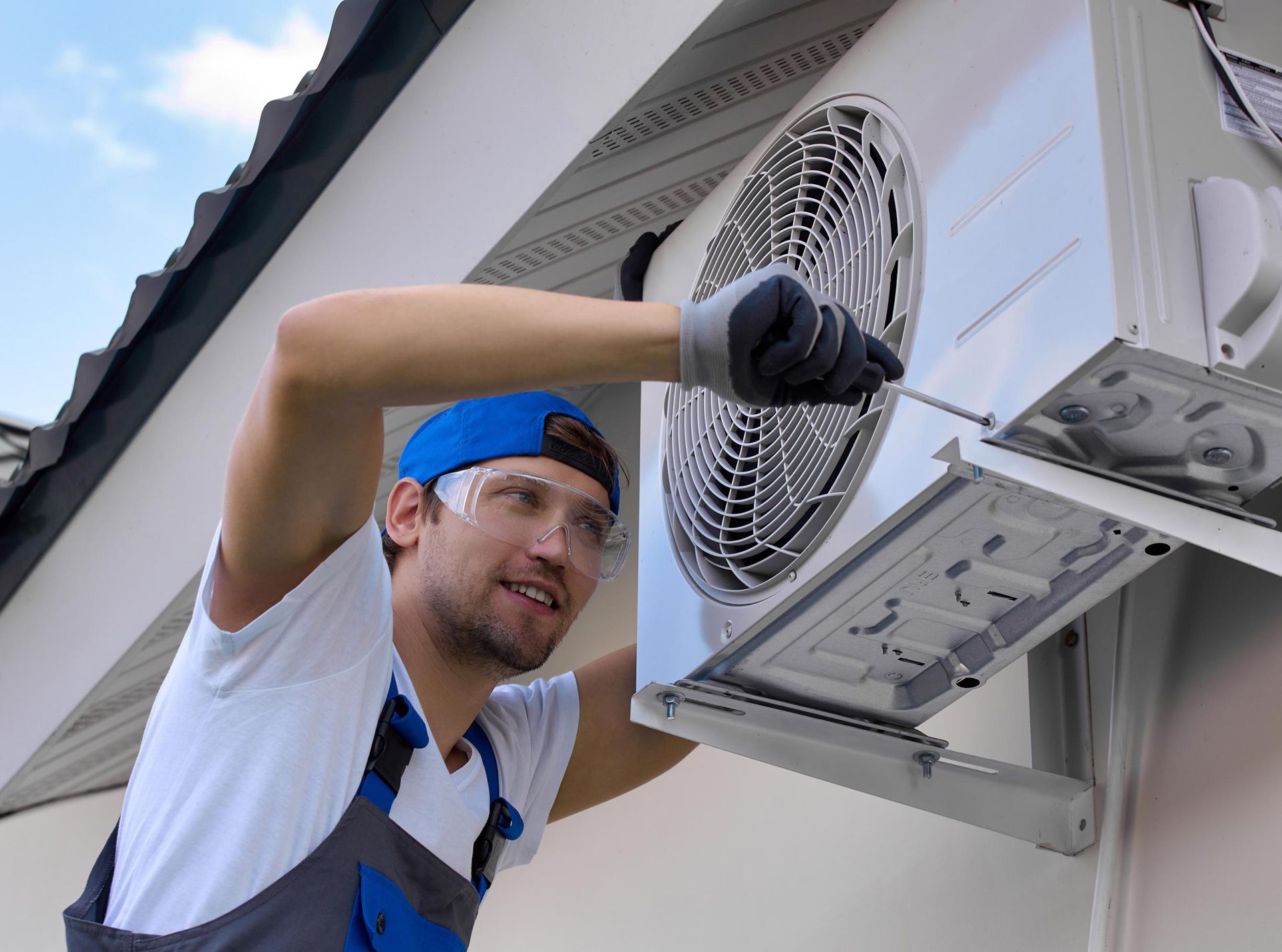 HVAC technician repairing an outdoor air conditioning unit on a building.