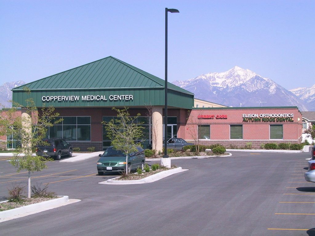 A green car is parked in front of a building that says cofferview medical center
