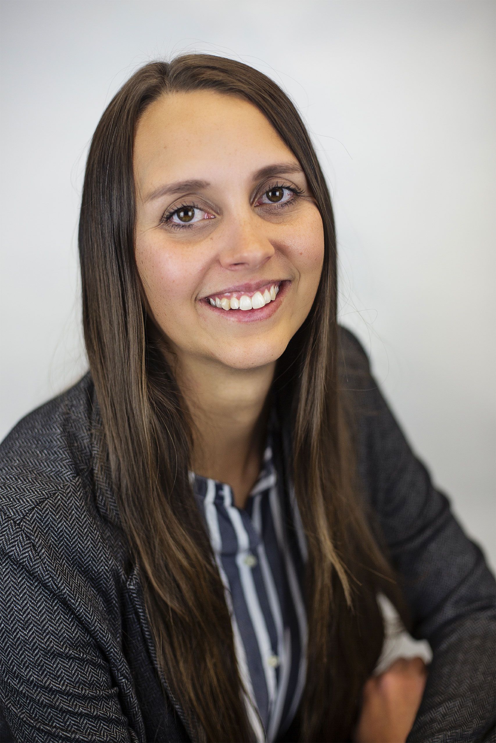 A woman with long hair and a striped shirt is smiling for the camera.