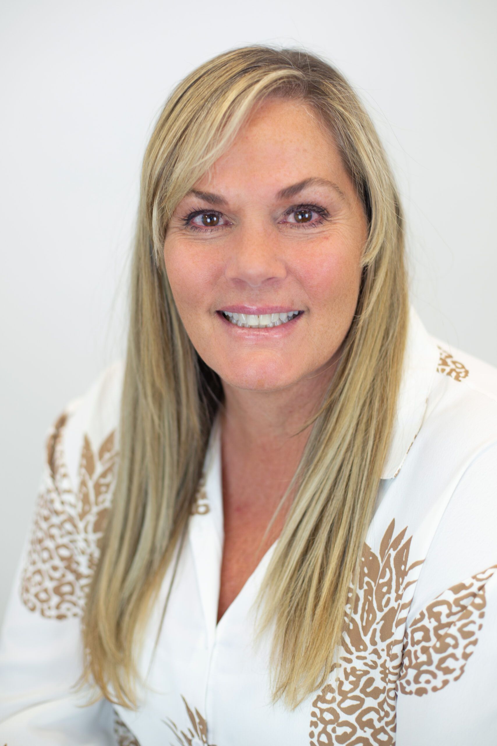 A woman wearing a white shirt with pineapples on the sleeves is smiling for the camera.