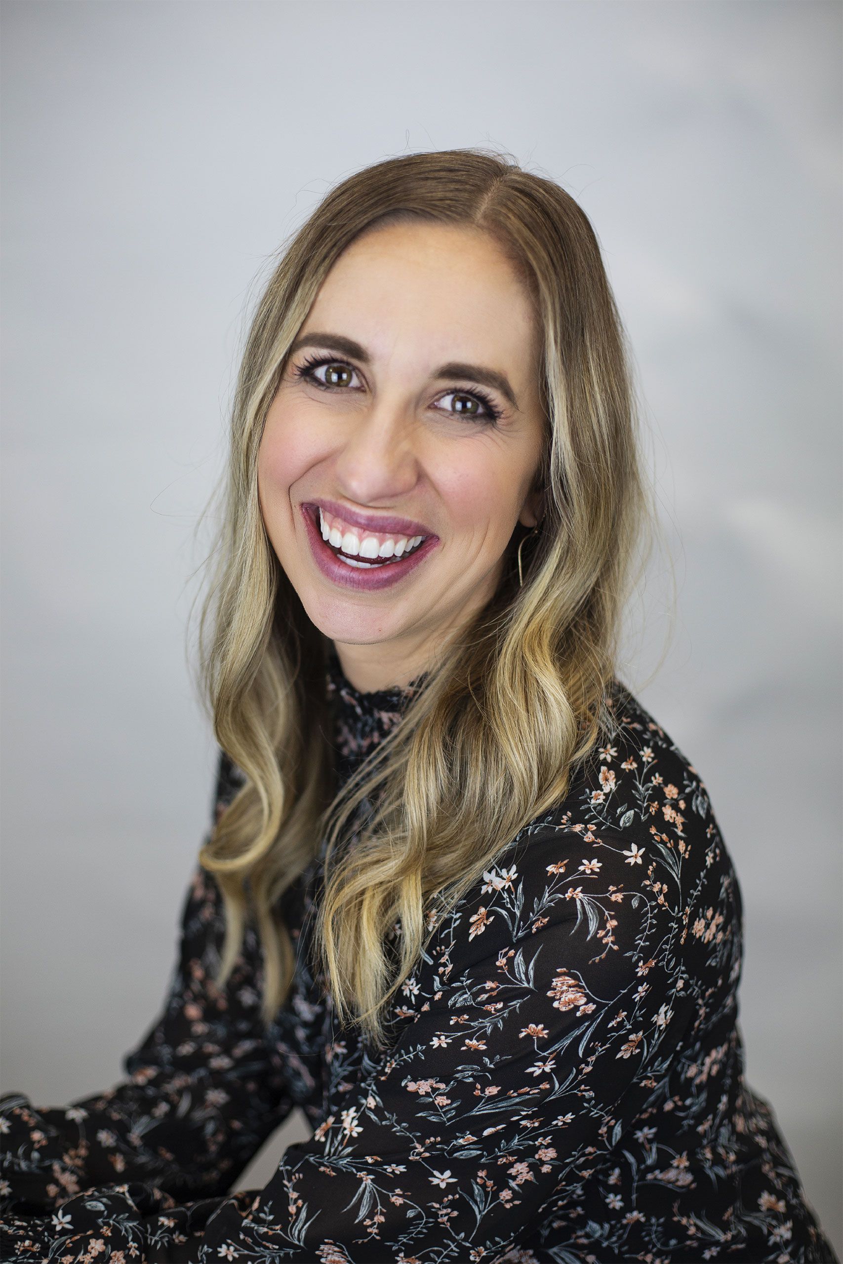 A woman in a floral dress is smiling for the camera.